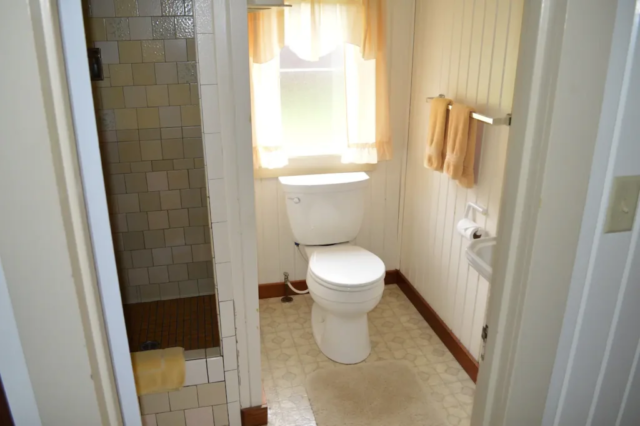 Bathroom with toilet, small wash basin, and tiled shower.